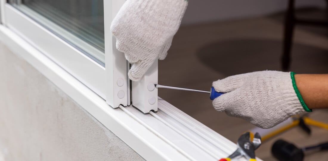 Close-up of gloved hands using a screwdriver on a sliding door