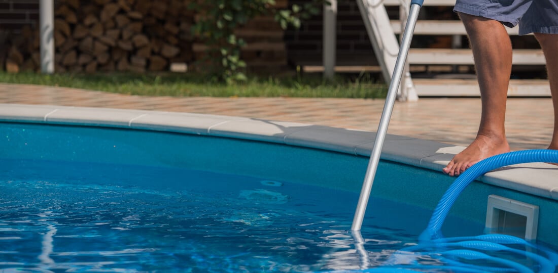 Person using a pool skimmer net on their swimming pool