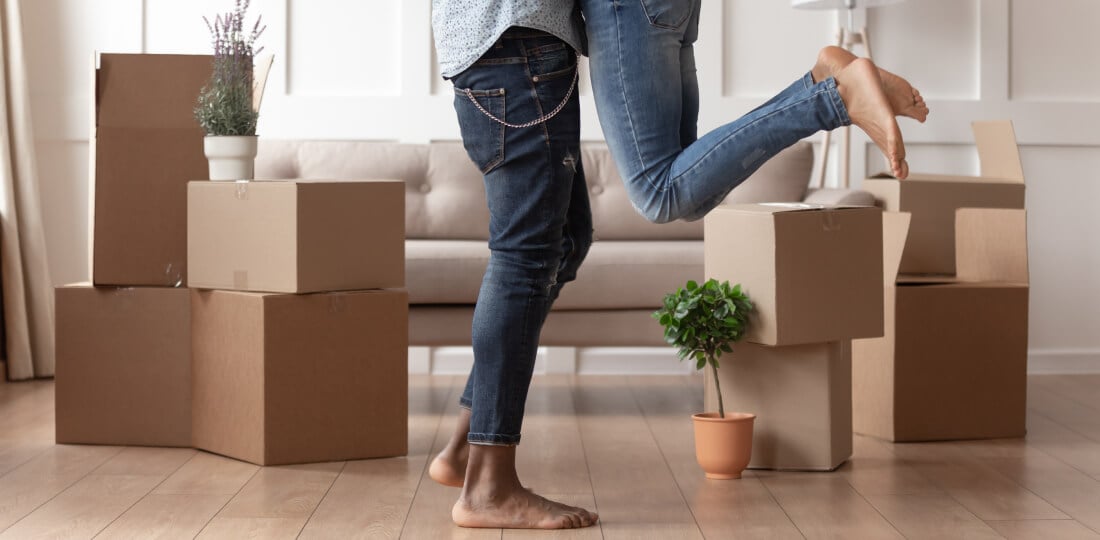 Couple hugging in living room filled with moving boxes